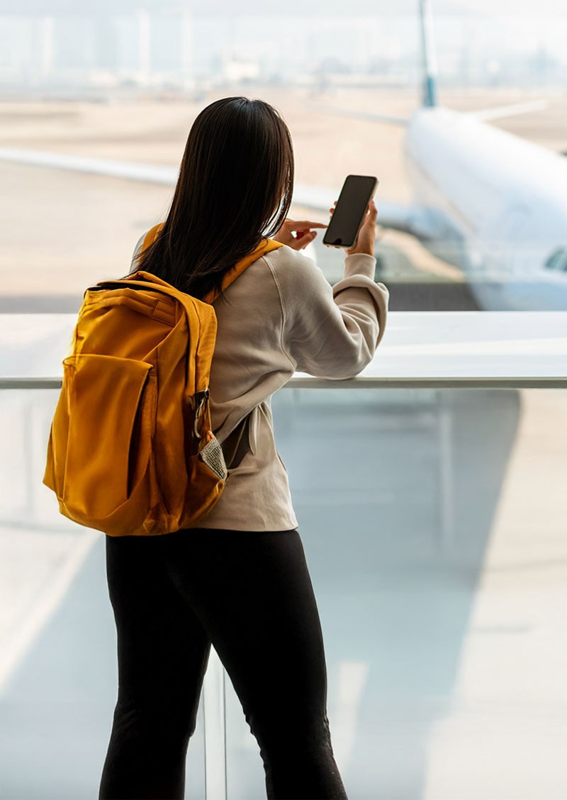A photograph of a woman using a VPN to safely access airport public Wi-Fi.