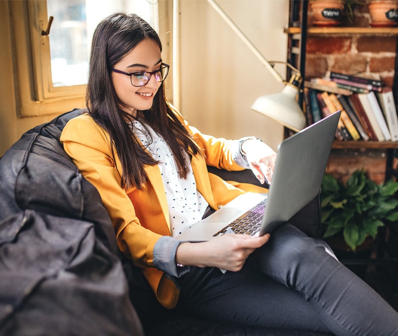 An image of a woman sitting in front of her laptop and checking whether she got a fake virus alert.