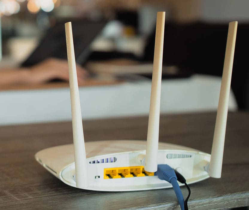 A Wi-Fi router sits on a computer desk shelf.