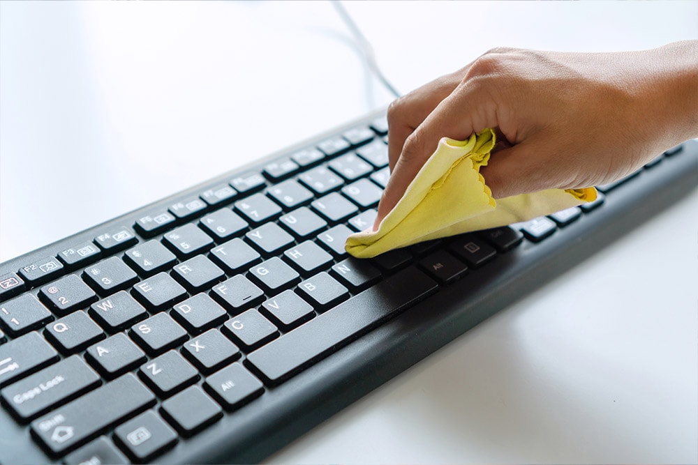 An image of someone wiping around the keys on a keyboard.