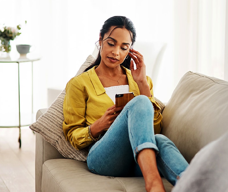 A woman looks at her phone and asks herself, "Is my phone hacked"?