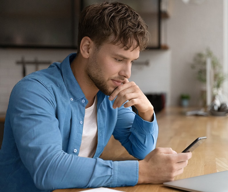 Person with a confused expression looking at their phone, potentially wondering 'How to tell if someone blocked your number?'