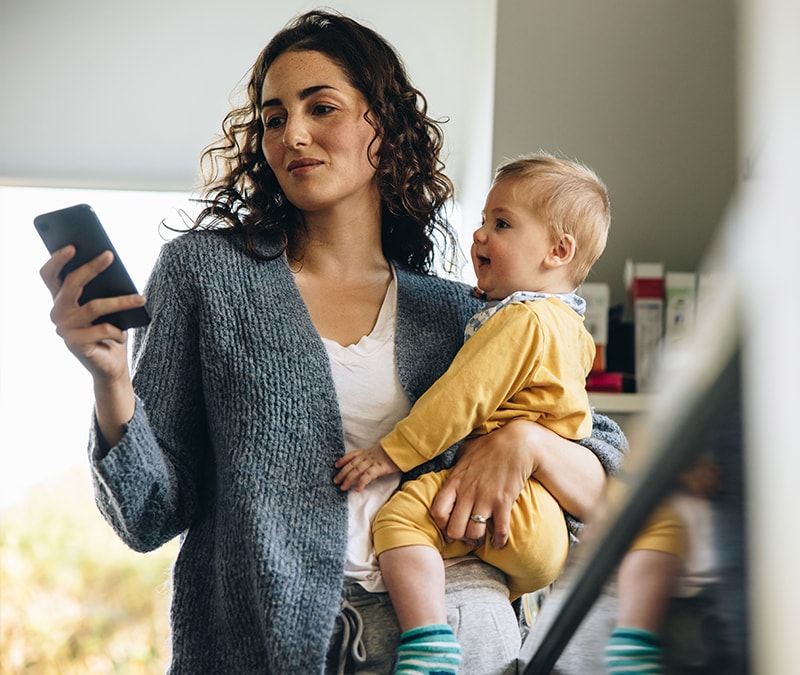A mother researching how to avoid WhatsApp scams while holding her child.