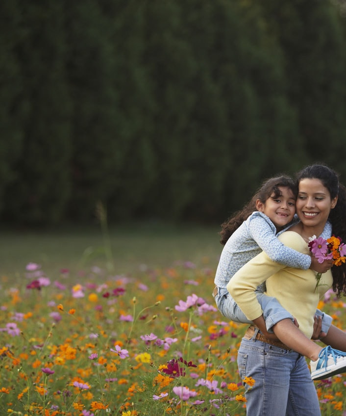 A family enjoying a sunny day in a flower field, a reminder of the importance of protecting our families from viruses.