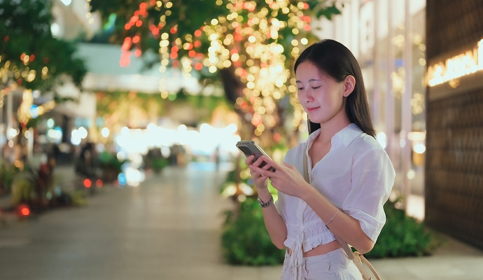 Kids lying down using tablet devices while mother in the background is tidying the kitchen.