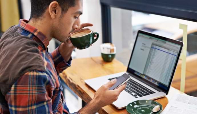 Man sitting in a coffee shop looking at a mobile phone