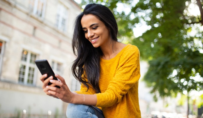 Woman in the street, smiling at her phone
